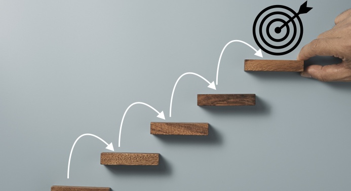 Nuolia puisilla porrasaskelmilla. Ylimmällä portaalla on piirros maalitaulusta, joka kuvastaa tavoitteen saavuttamista.