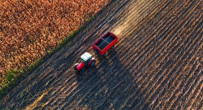 Lintuperspektiivistä kuvattu traktori pellolla auringonpaisteessa.