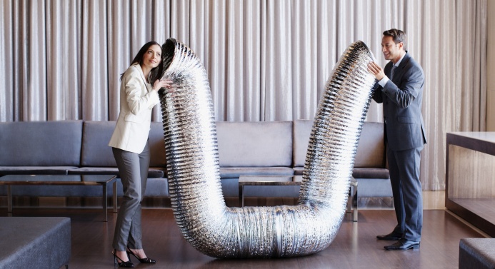 Kaksi toimistotyöntekijää puhuu toisilleen ison putken kautta.