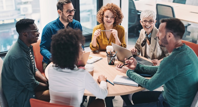Ryhmä keskustelee iloisesti pyöreän pöydän äärellä.