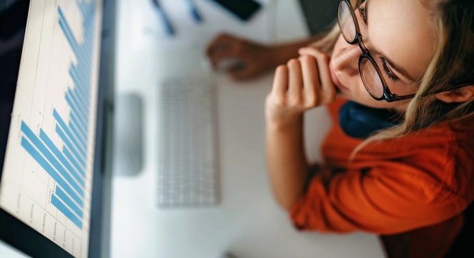 Ylhäältä otettu kuva, jossa nainen katsoo tietokoneen näytöltä kuvaajaa.