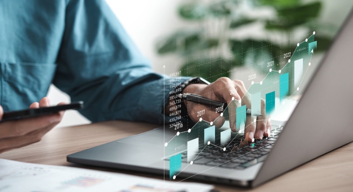 Henkilö käyttää tietokonetta, kuvan päällä graafielementtejä